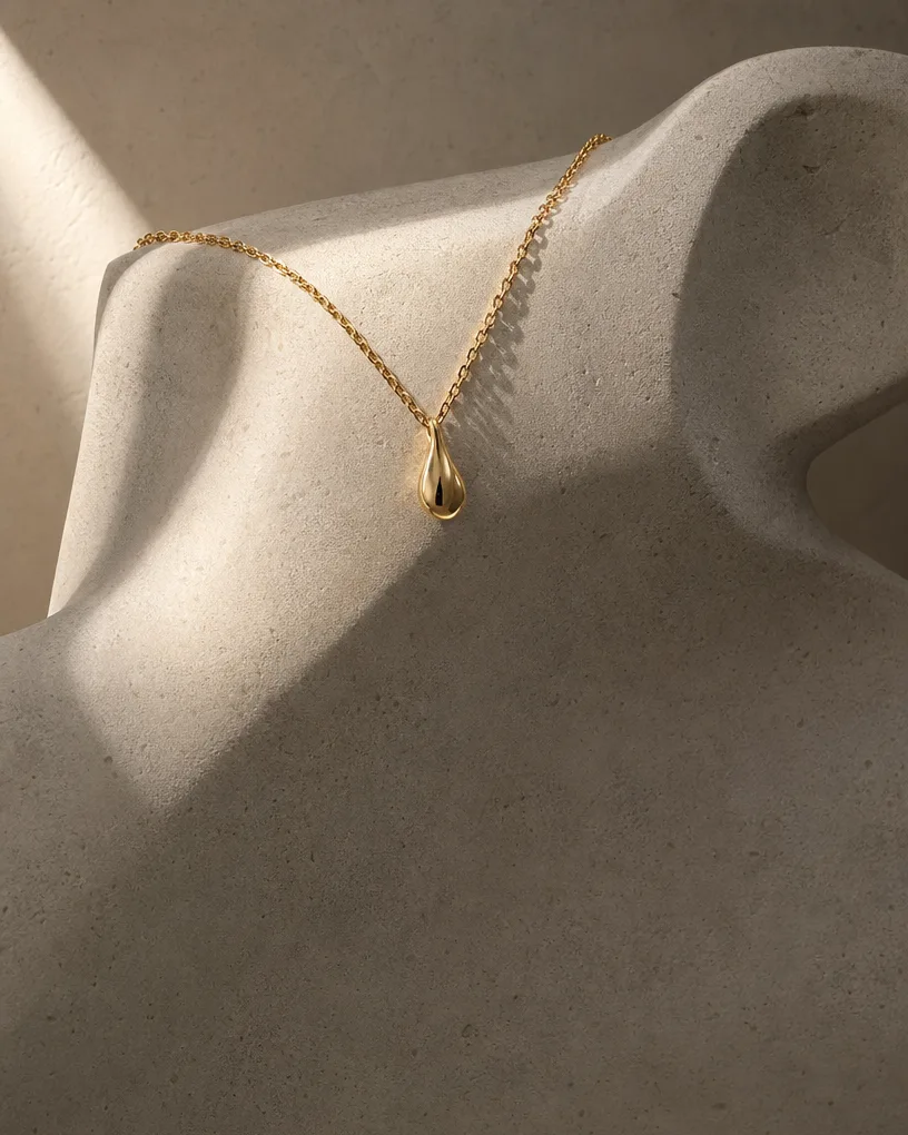 Gold necklace draped over a sculptural stone form