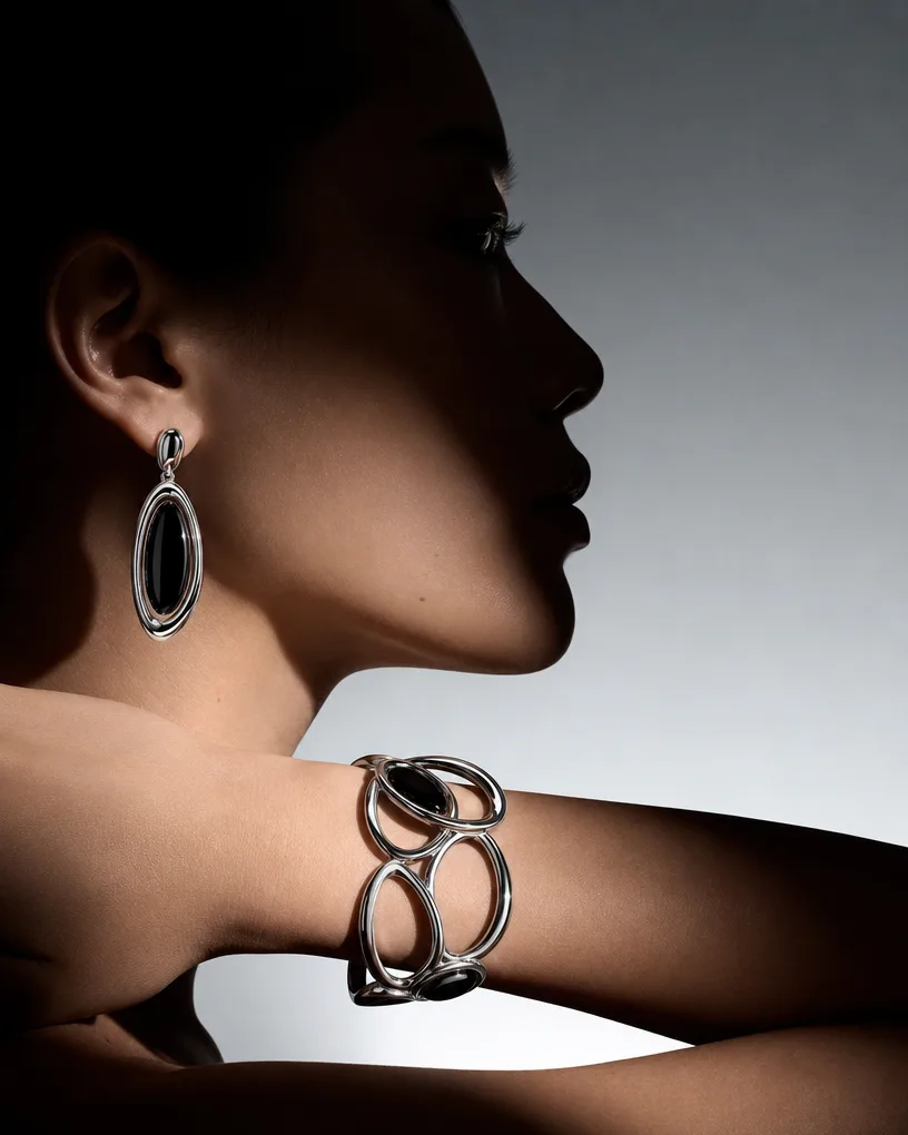 Model in profile with a black onyx drop earring and a chunky silver link cuff